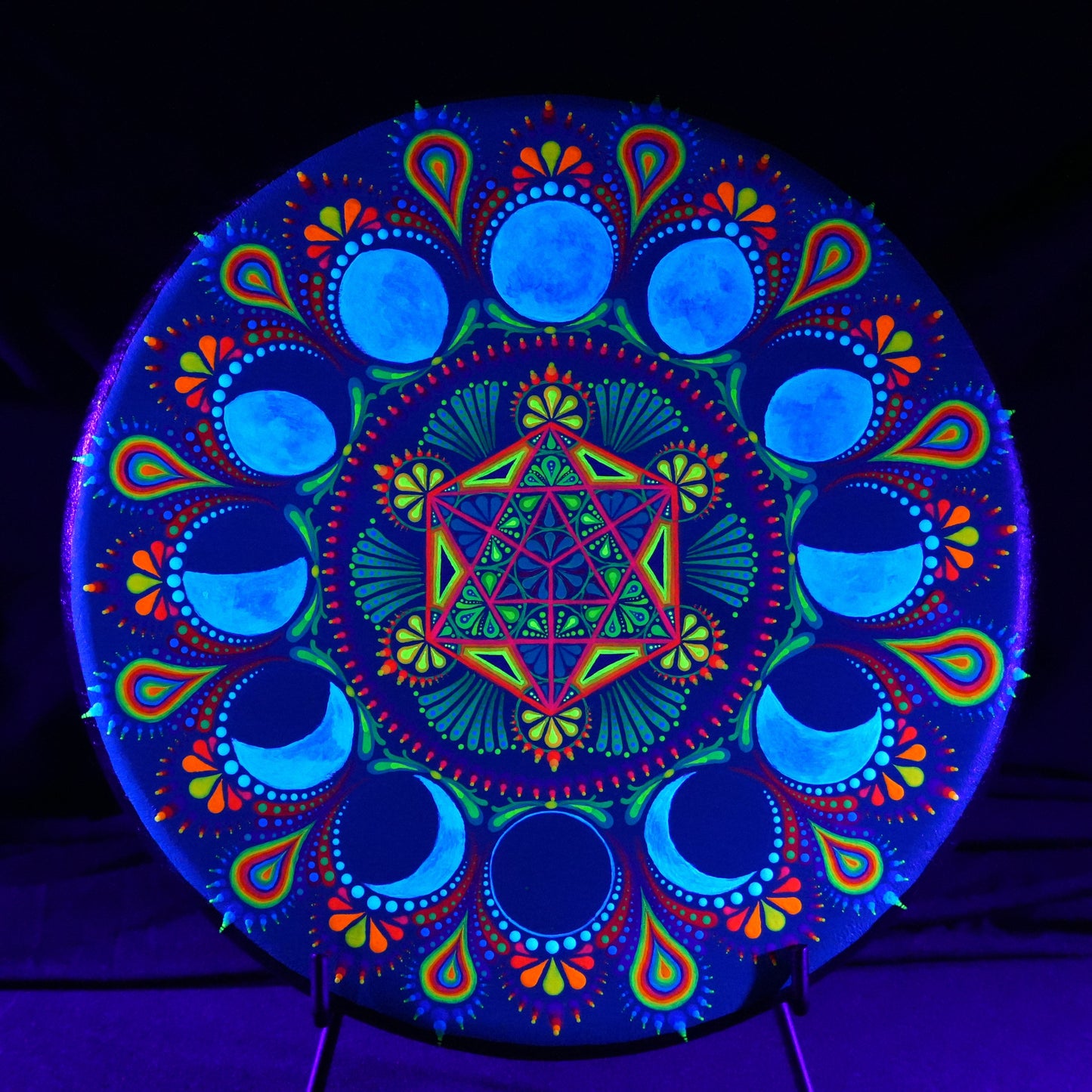 Colorful mandala design under black light on a dark background